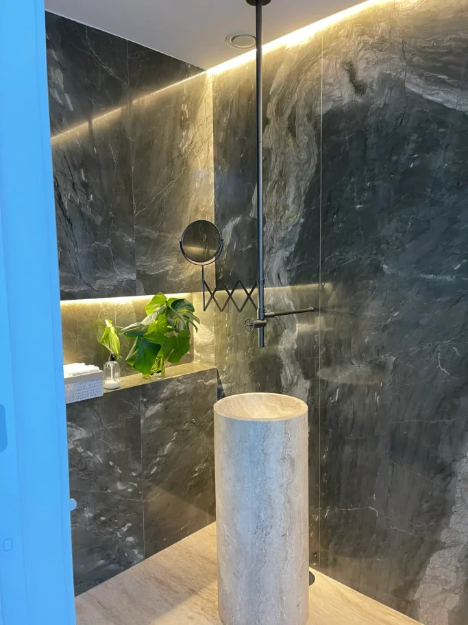 Detalle de reforma de baño de lujo revestido en mármol con grifería empotrada por Valandecor.