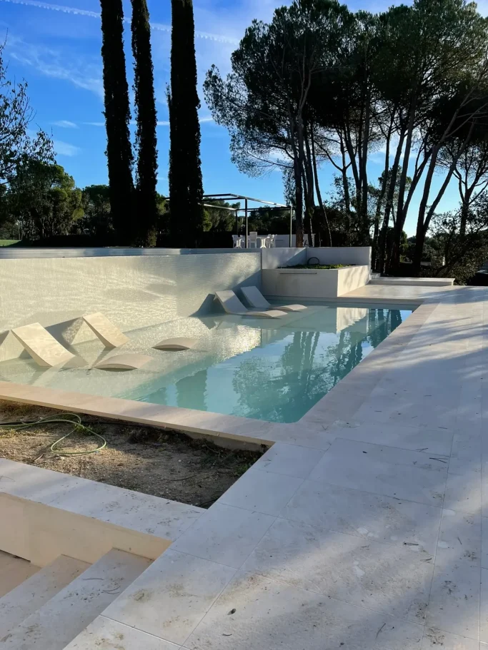 Construcción de piscina de obra con sillones de hidromasaje integrados en jardín de chalet.