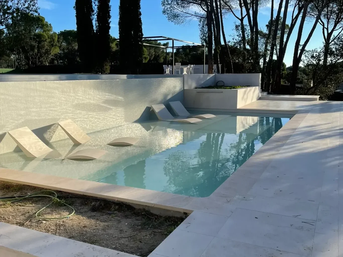 Diseño y construcción de piscina moderna integrada en el jardín de un chalet en Madrid.